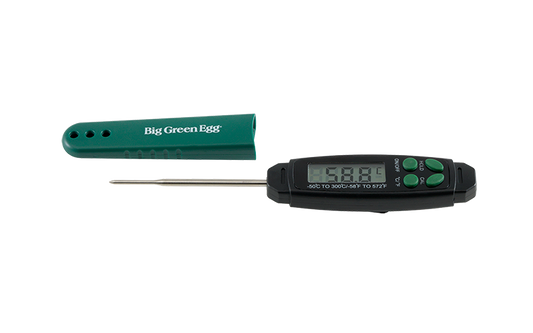 Een digitale thermometer van Big Green Egg. Het apparaat heeft een zwart displaygedeelte met knoppen en een metalen meetpen. Ernaast ligt een groene beschermhoes met het logo "Big Green Egg". De thermometer is ontworpen om snel en nauwkeurig de temperatuur van voedsel te meten, met een meetbereik van -50°C tot 300°C.