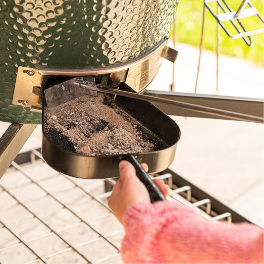 Iemand houdt de Ash Removal Pan voor de onder-airflow-schuif en zorgt er onderrtussen met de aspook voor dat de as in de Removal Pan blijft.